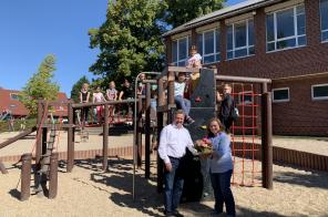 Einige Grundschulkinder auf der neuen Spielkombination hinter Bürgermeister Clemens Brüx und Schulleitung Jessica Claassen