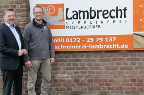 Bürgermeister Clemens Brüx und Herr Lambrecht vor dem Unternehmensschild
