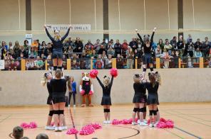 Cheerleader machen eine Hebefigur vor der Tribüne