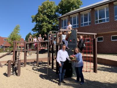 Einige Grundschulkinder auf der neuen Spielkombination hinter Bürgermeister Clemens Brüx und Schulleitung Jessica Claassen