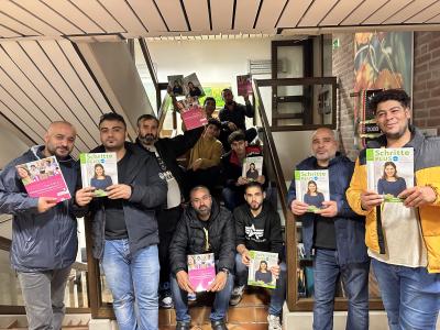Teilnehmer der Sprachkurse halten ihre Bücher hoch