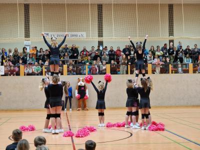 Cheerleader machen eine Hebefigur vor der Tribüne