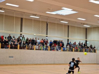 Die Tribüne beim Kinderfußballturnier im Hintergund und 2 rennende Kinder im Vordergrund